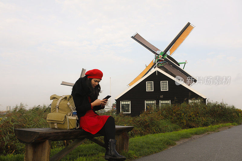 在阿姆斯特丹Zaanse Schans旅游期间使用手机的亚洲女性